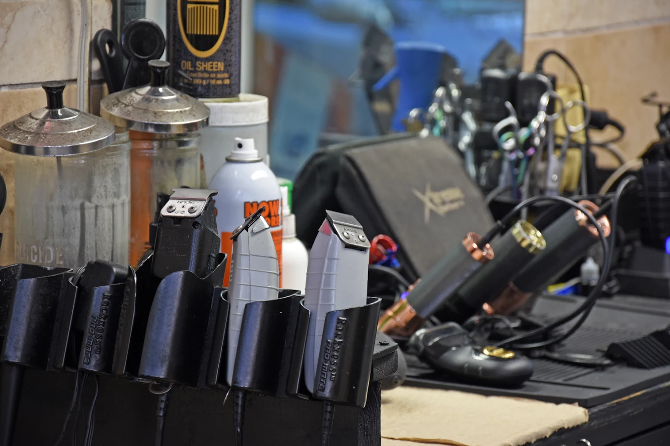 Classic barber tools including a straight razor, clippers, scissors, and shaving brush on worn leather